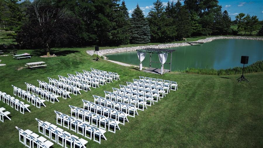 Aerial angle of a wedding ceremony arbor and seating set up beside a pond in Fox Valley, WI