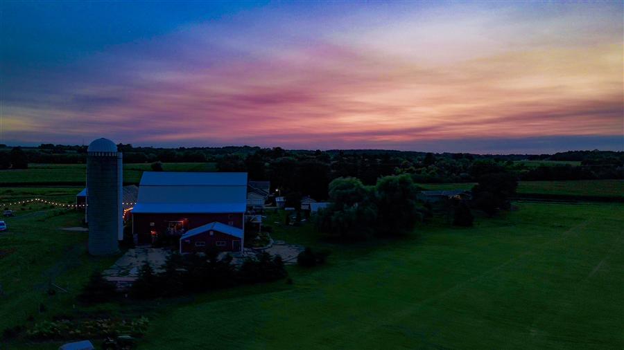 Aerial photo of a barn wedding venue at sunset with string lights